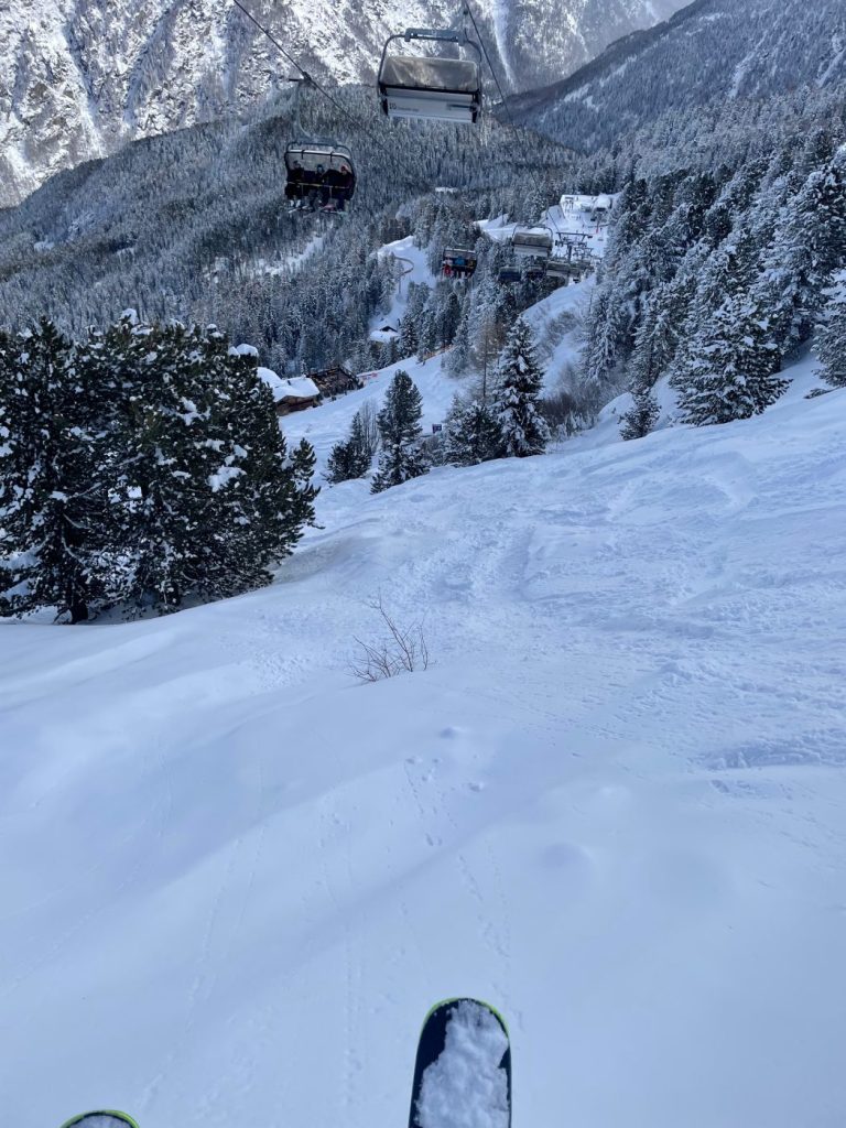 Gondelbahn schwebt über tief verschneitem Nadelwald
